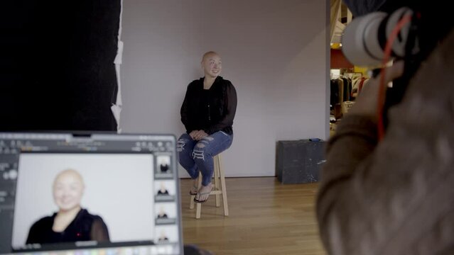 Behind the scenes shot of a photographer taking photos of a bald woman with alopecia on a set