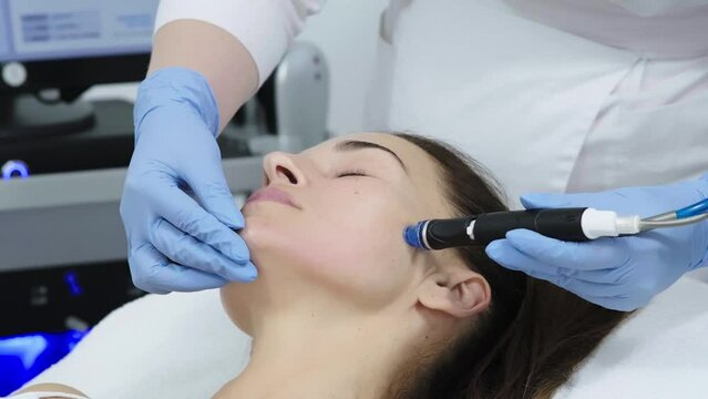 A doctor performs cosmetic procedures for rejuvenation and facial cleansing on a middle-aged patient in a cosmetology clinic. Hydropic cosmetic procedure, facial cleansing, clean skin.