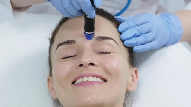 A doctor performs cosmetic procedures for rejuvenation and facial cleansing on a middle-aged patient in a cosmetology clinic. Hydropic cosmetic procedure, facial cleansing, clean skin.