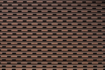 A close-up background photo of an old roller shutter in a garage with many holes in the design