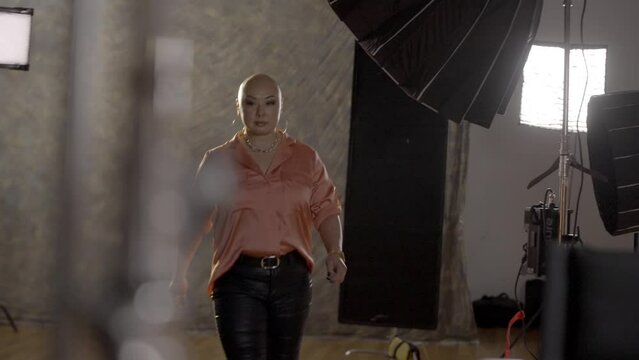 Woman with alopecia walks onto a film set and looks at the camera