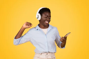 Poster Joyful woman with headphones dancing to music isolated © Prostock-studio