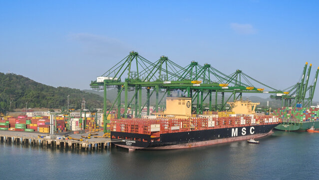 Panama City, Panama - 23 January 2024: Wide angle view of cranes unloading the container ship MSC Cassandre docked in the port of Panama City