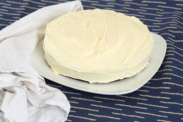 Whole round cake with delicate white frosting.	