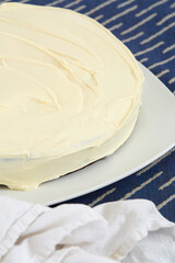Whole round cake with delicate white frosting.	