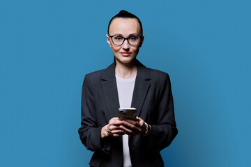 Adult smiling woman with smartphone on blue studio background