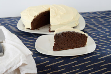 Slice of dark chocolate cake with delicate white frosting.