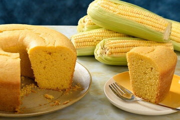  Corn cake on a plate on a yellow marble base, a slice of cake on a plate, ears of green corn on...