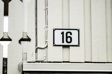 Number 16 on the facade of a baige house.