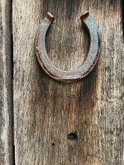 Rustic metal lucky horseshoe on a weathered wooden wall.
