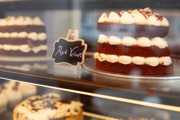photograph of cakes and desserts inside a display case in a bakery. close-up of red velvet cake
