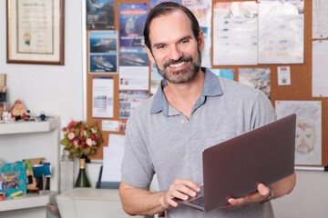 Tourism agent working from his agency with laptop in hand