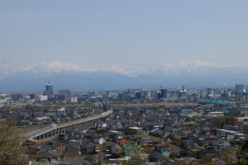 満開の桜春霞の薬師岳北アルプス立山連峰と神通大橋と富山市街地