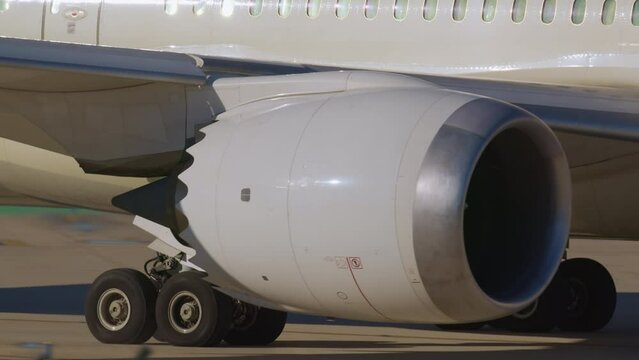 Close-up of an aircraft jet engine and landing gear on a runway