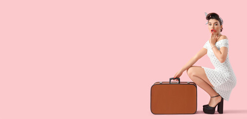 Shocked young pin-up woman with suitcase on pink background