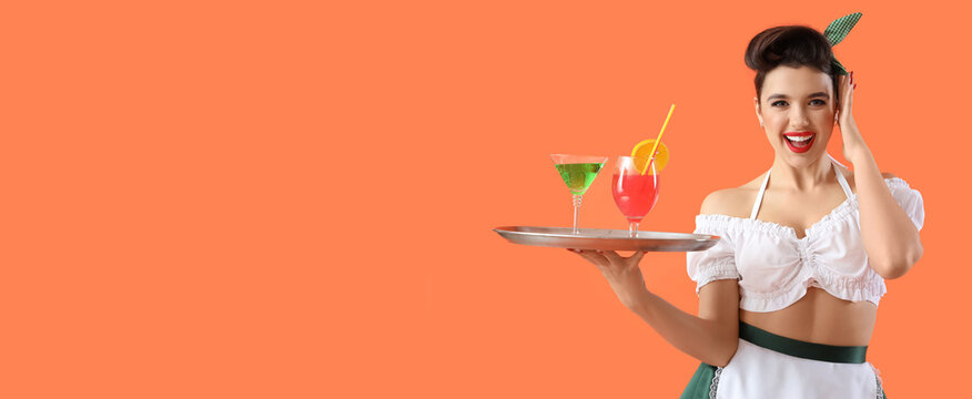 Young pin-up waitress with cocktails on orange background