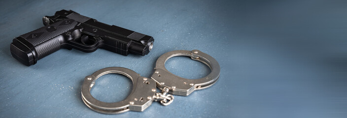 Gun and handcuffs on blue background, stock photo, criminal concept