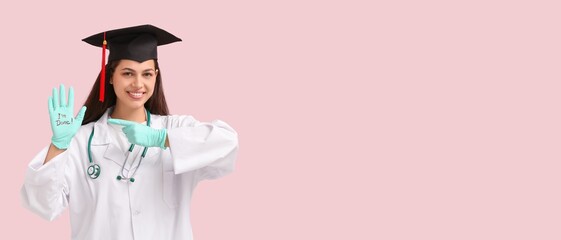 Female medical graduating student on pink background with space for text