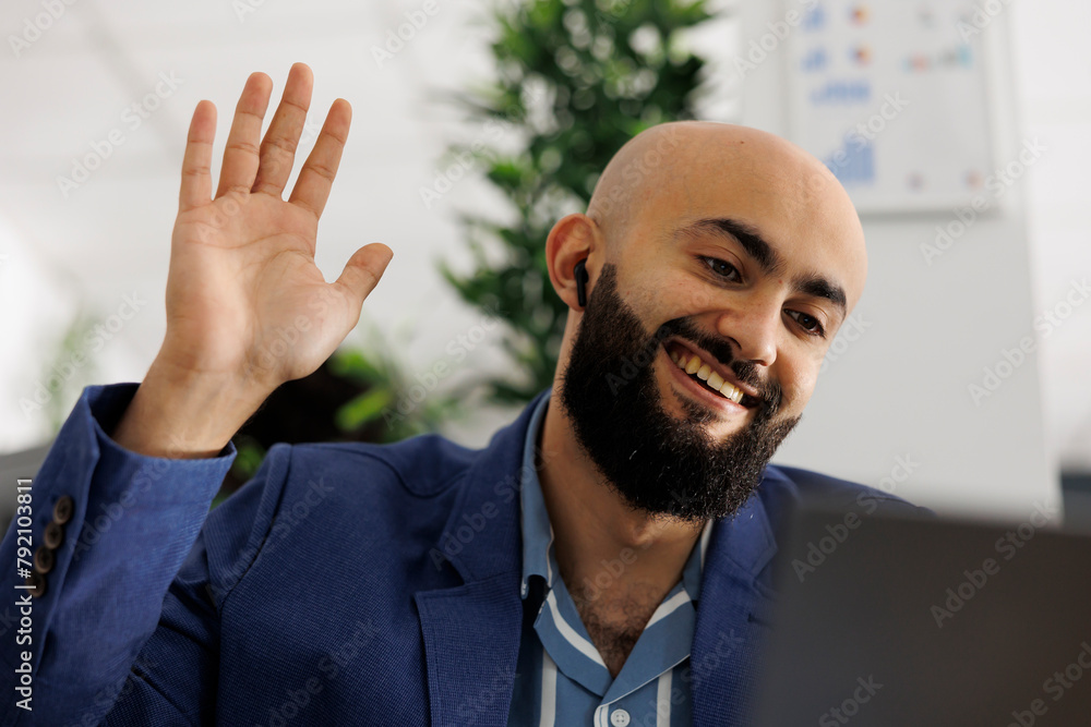 Poster smiling entrepreneur attending remote conference call and greeting employees. arab executive manager
