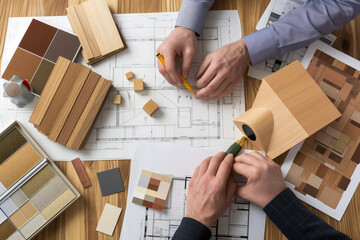 Architectural planning and interior design collaboration. Two professionals engage in selecting materials and refining a floor plan for a home renovation project.