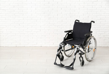 Empty wheelchair near white brick wall