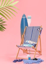 Deckchair, beach accessories and glass of cocktail on pink background