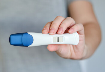 Close up of a woman holding a digital positive pregnancy test