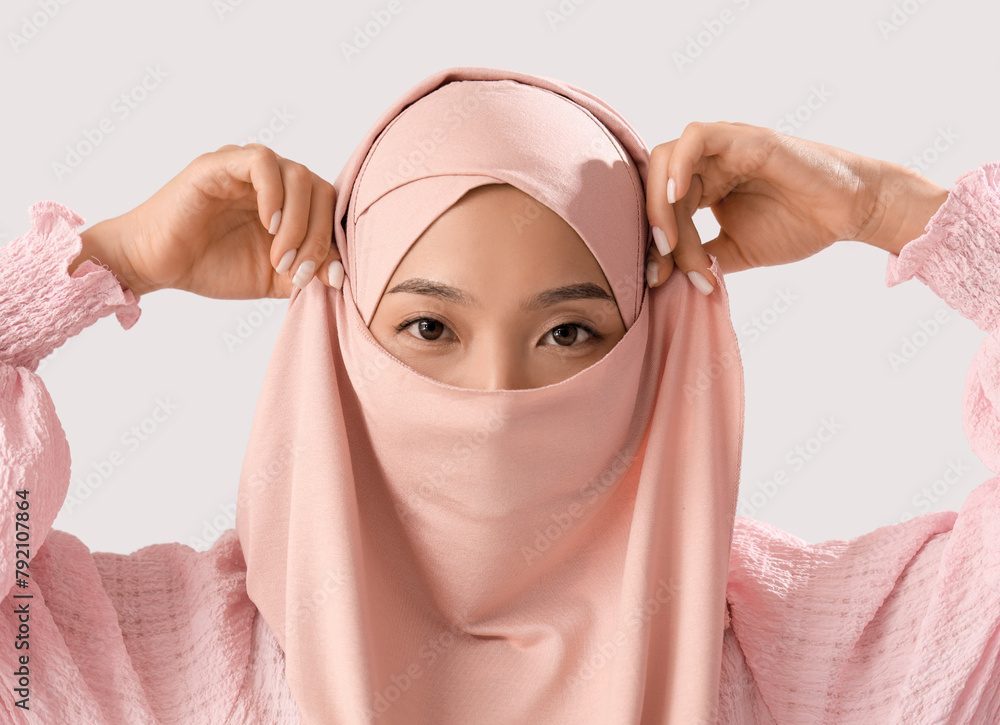 Sticker Beautiful young Asian woman in hijab on grey background