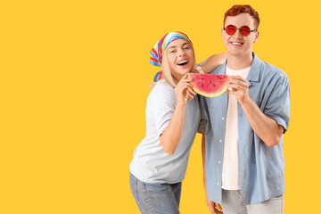 Young beautiful man and woman with slice of fresh watermelon on yellow background