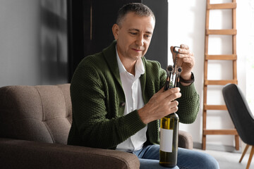 Mature man opening bottle of wine at home