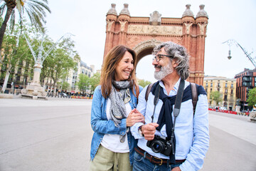 Mature love couple standing looking at each other with affection holding arms outdoor in European...