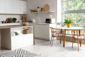 Interior of modern kitchen with white furniture and wooden island table