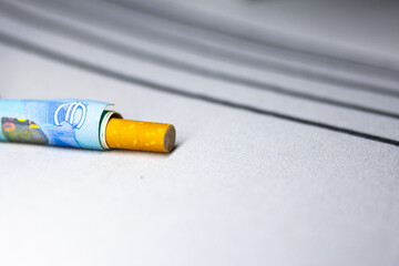 A cigarette butt is on a white surface with a bill in the background