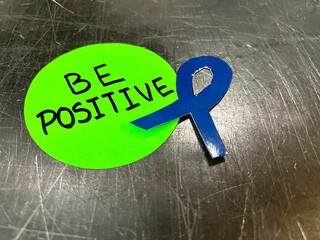 A sticker with the word "be positive" written on it is placed on a metal surface