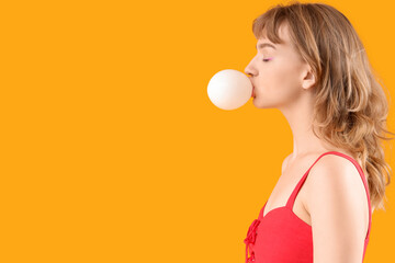 Beautiful young woman with chewing gum on yellow background