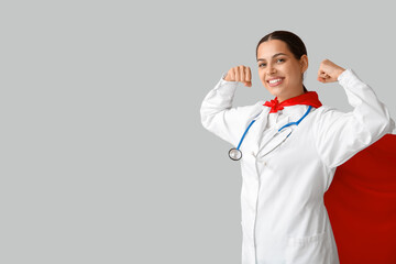 Beautiful female doctor in superhero costume showing muscles on white background
