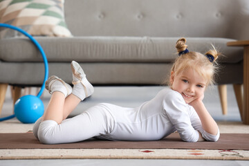 Naklejka premium Cute little girl lying on fitness mat at home