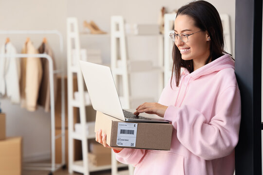 Female seller with parcel using laptop in warehouse store