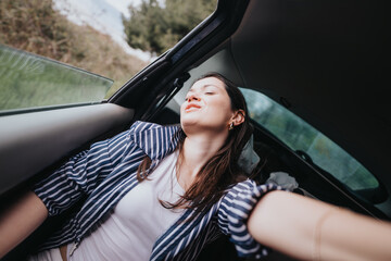 Captured with her eyes closed, this young woman exudes relaxation and joy as she breathes in fresh air during a scenic car ride.