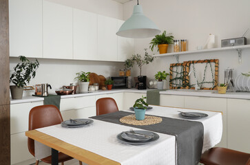 Interior of modern kitchen with green plants, dining table and counters