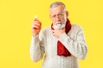 Old man with sore throat holding spray on yellow background