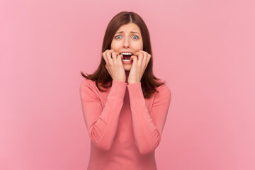 Nervous woman bites finger nails with embarrassment, worries as has deadline to prepare task, has...