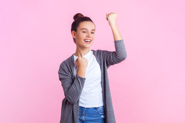 Portrait of cheerful positive teenage girl with bun hairstyle in casual clothes standing...