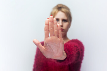 Portrait of confident strong young blonde woman standing showing stop gesture prohibition...