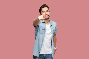 Portrait of serious strict bearded man in blue casual style shirt standing pointing index finger at...