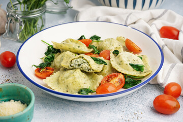 Bowl of tasty ravioli with vegetables on grey background