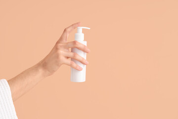 Female hand with bottle of cream on color background