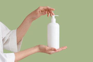 Woman holding bottle of cream against green background