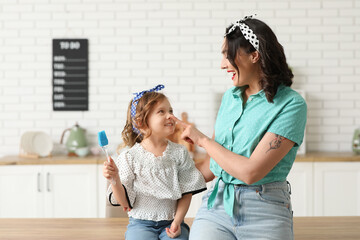 Beautiful pin-up woman and her daughter with cooking utensil in kitchen