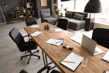 Table with stationery and armchairs prepared for business meeting in modern conference hall